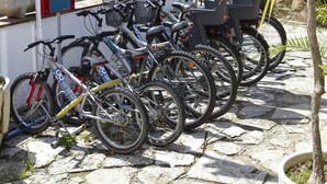 A row of bicycles parked in front of a building with a sign indicating a reception area. - Hotel Bell Repos (Castell-Platja d'Aro)