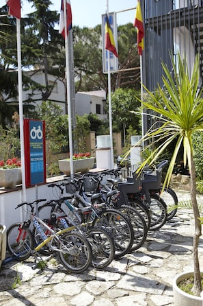 A row of bicycles parked in front of a building with a sign indicating a reception area. - Hotel Bell Repos (Castell-Platja d'Aro)