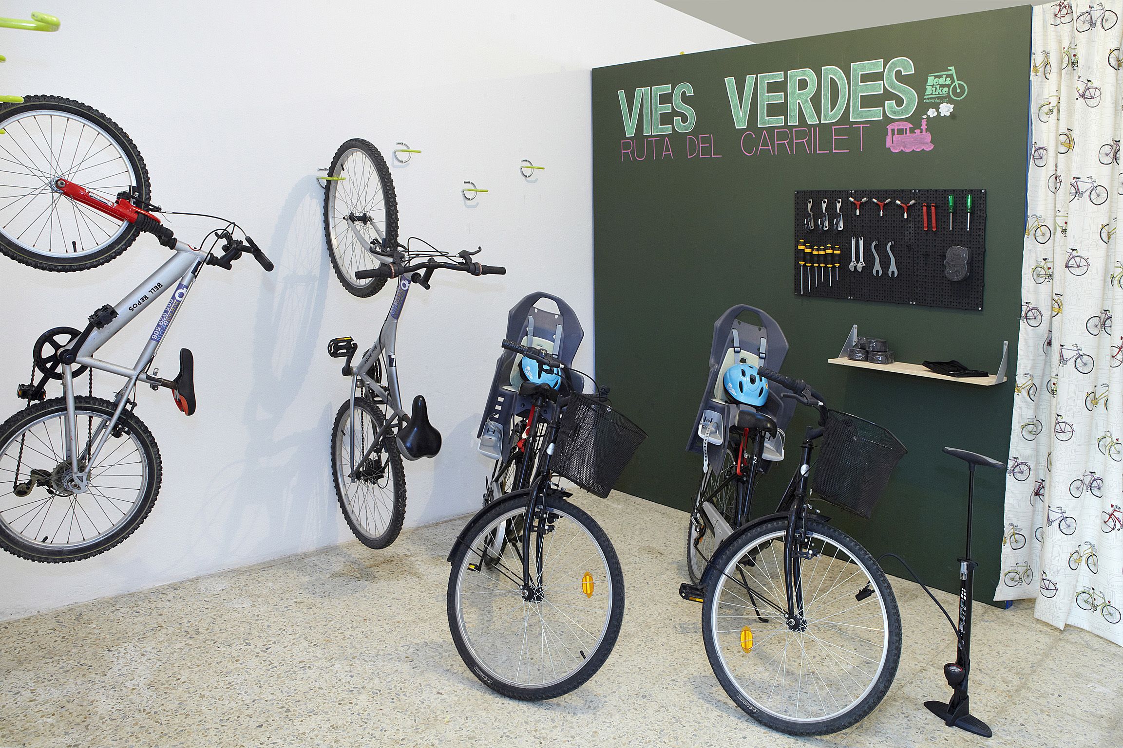 Un atelier de réparation de vélos équipé d’outils et d’une pancarte indiquant : « Vies Verdes Ruta del Carrilet ».