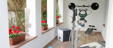 A home gym with exercise equipment, a wall-mounted cartoon character, and potted plants.