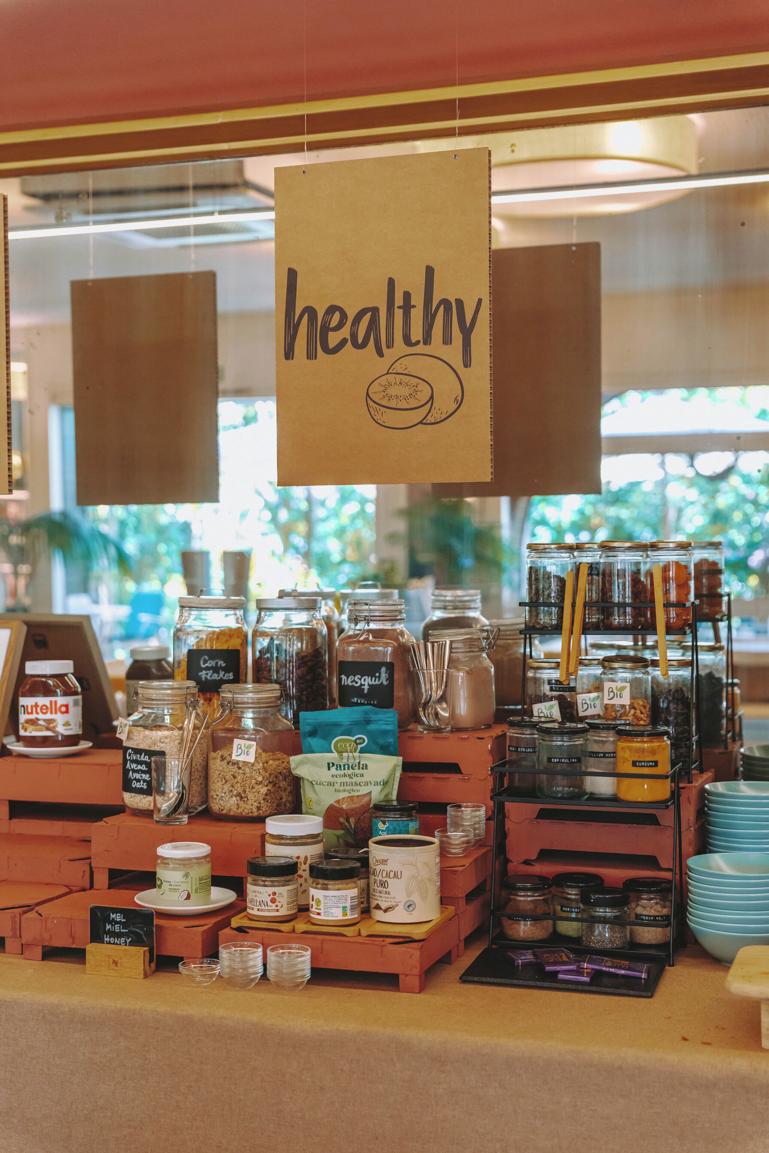A variety of jars and containers with labels, some with 'Bio' and 'Nutella' visible, and a sign that reads 'healthy' hanging above.