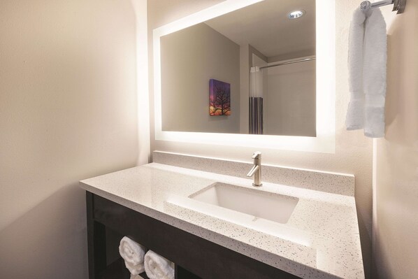 A bathroom with a white speckled sink, a large mirror, and a towel rack. - La Quinta Inn & Suites by Wyndham Terre Haute (Terre Haute)