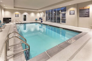 An indoor swimming pool with clear pool rules and a lifeguard chair.