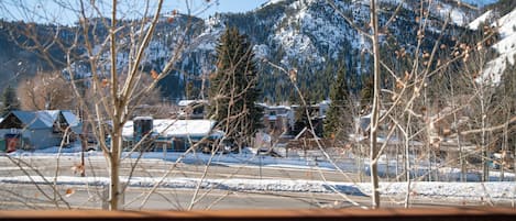 A view of a snowy mountain landscape with buildings in the foreground.