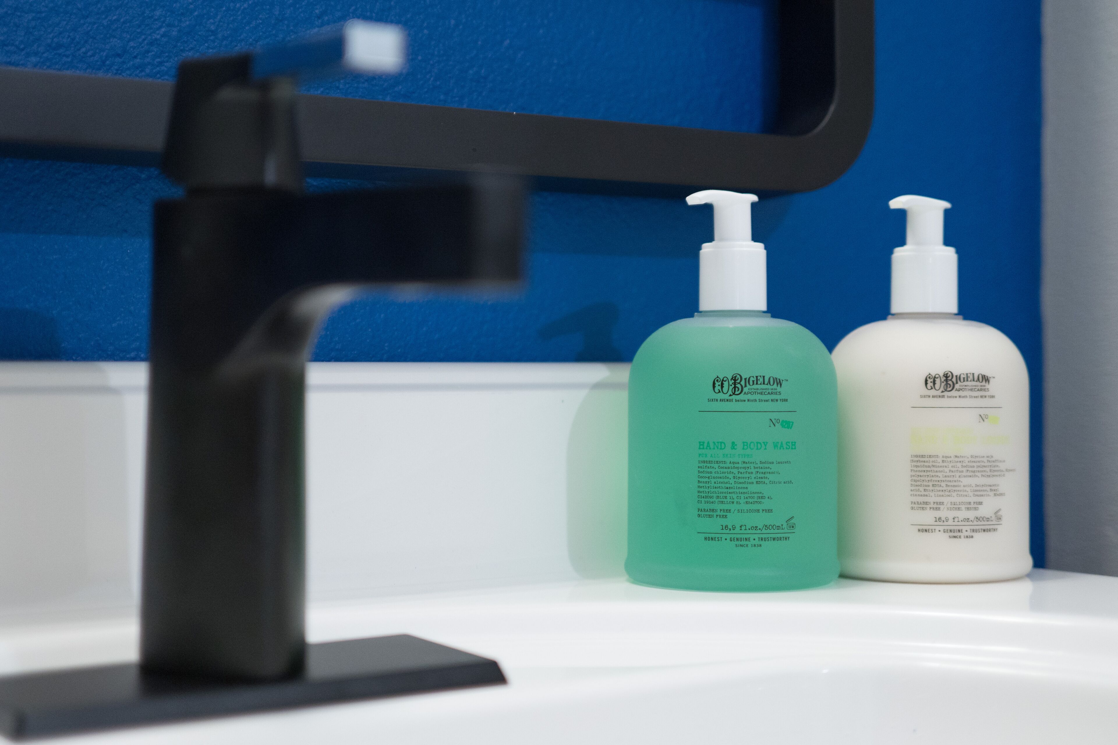 A bathroom sink with two hand and body wash bottles and a black faucet.