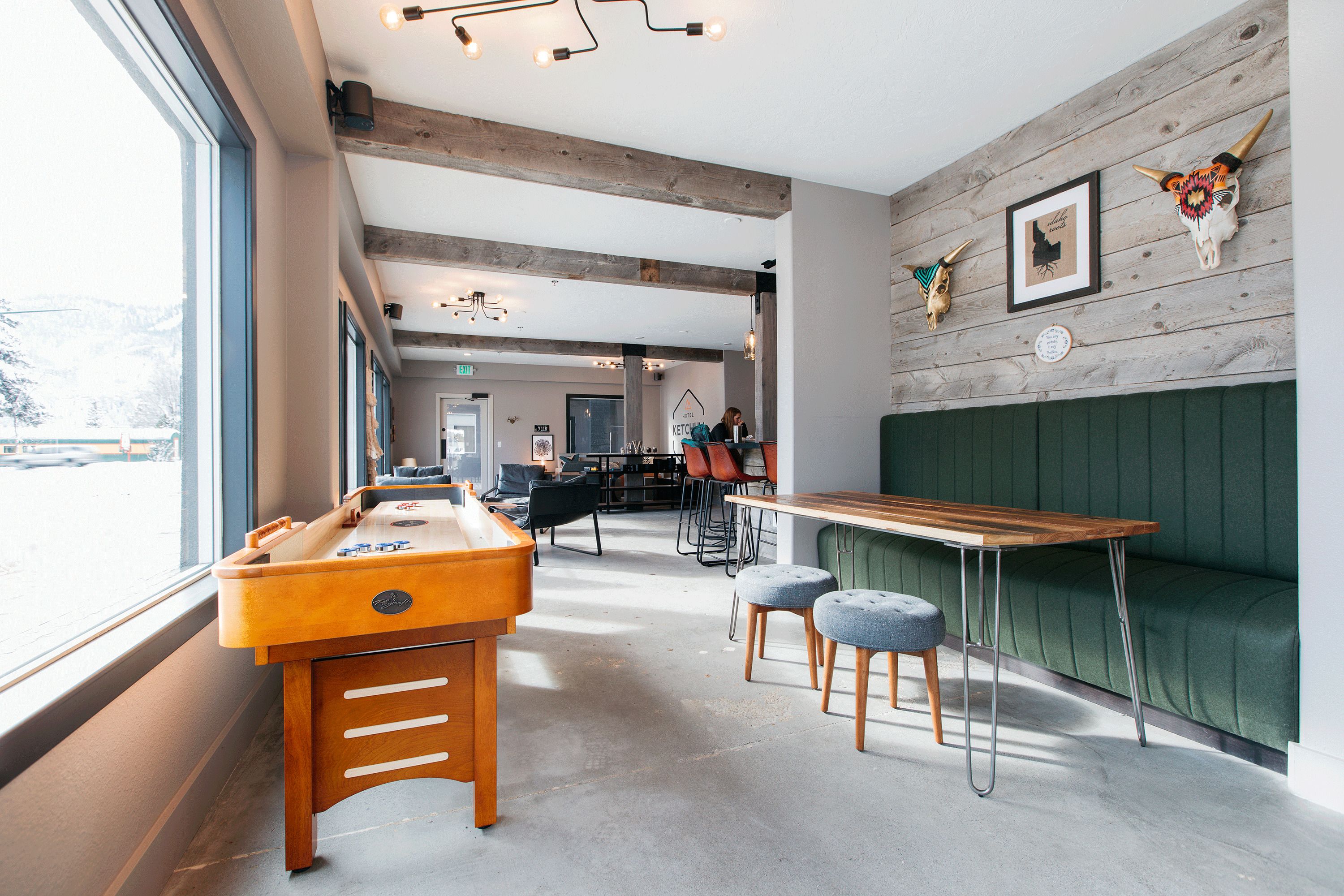 A cozy bar area with a wooden table, stools, and a green cushioned bench.