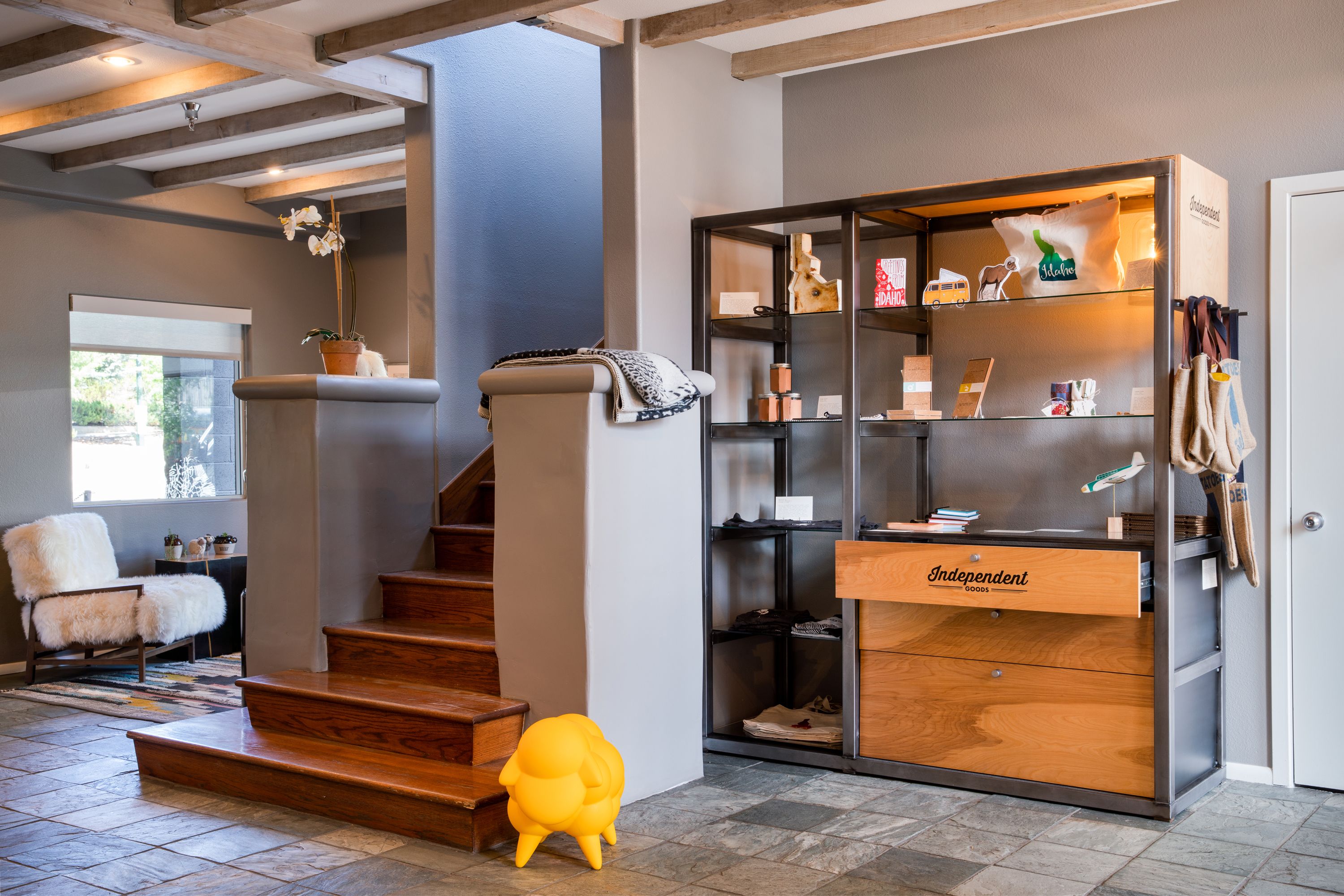 Een modern interieur met een trap, een zachte fauteuil, een houten kast en een klein geel voorwerp op de vloer.