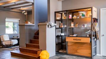 A modern interior with a staircase, a fluffy chair, a wooden cabinet, and a small yellow object on the floor.