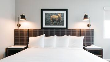 A neatly made bed with white linens, a plaid headboard, and two bedside lamps.
