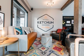 A modern hotel lobby with a sofa, chairs, a coffee table, and a colorful carpet.