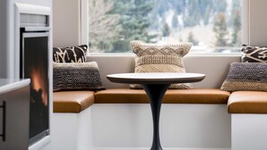 A cozy seating area with a round table, a hanging light fixture, and a window with a view of trees. - Hotel Ketchum (Ketchum)