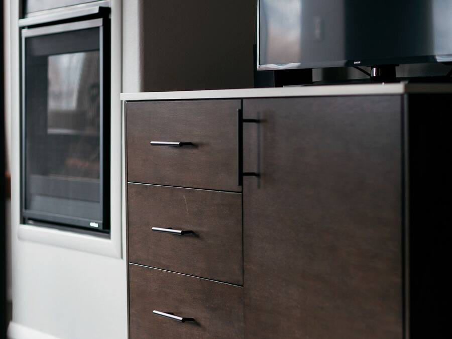 Una cocina moderna con horno empotrado y un mueble de madera oscura con cajones.