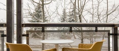 A covered outdoor seating area with two yellow wicker chairs and a small round table.