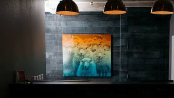 Un intérieur moderne avec un grand tableau abstrait sur un mur texturé, des luminaires suspendus et un design minimaliste.