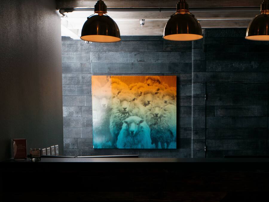 Un intérieur moderne avec un grand tableau abstrait sur un mur texturé, des luminaires suspendus et un design minimaliste.