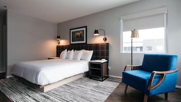 A bedroom with a bed, bedside tables, a chair, a window, and a picture on the wall.