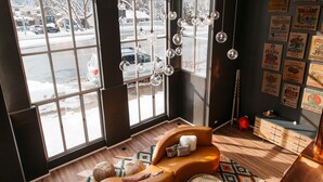 A modern living room with a large window, a brown leather sofa, a patterned rug, and a wooden coffee table. - Hotel Ketchum (Ketchum)