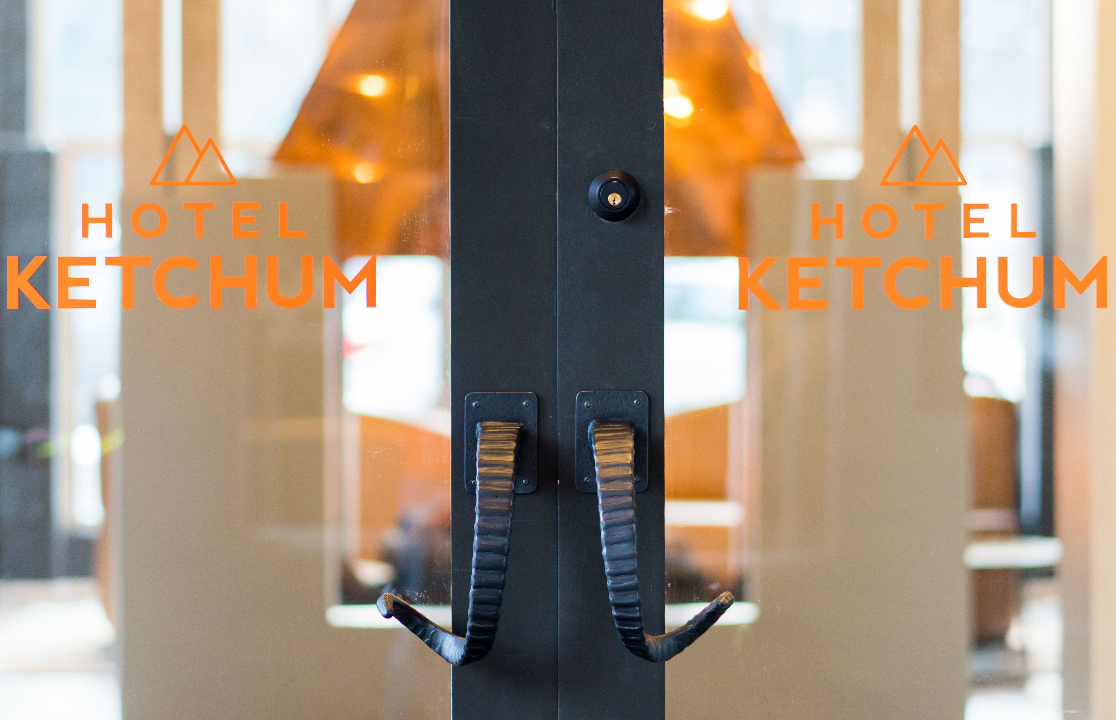 En hotellentrél med modern design, med en glasdörr och två svarta handtag.