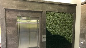 An elevator with a metallic finish and a wall with a textured pattern.
