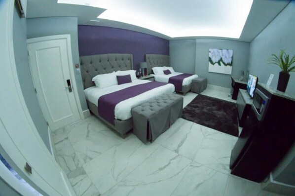A modern bedroom with two beds, a large window, and a flat-screen TV.