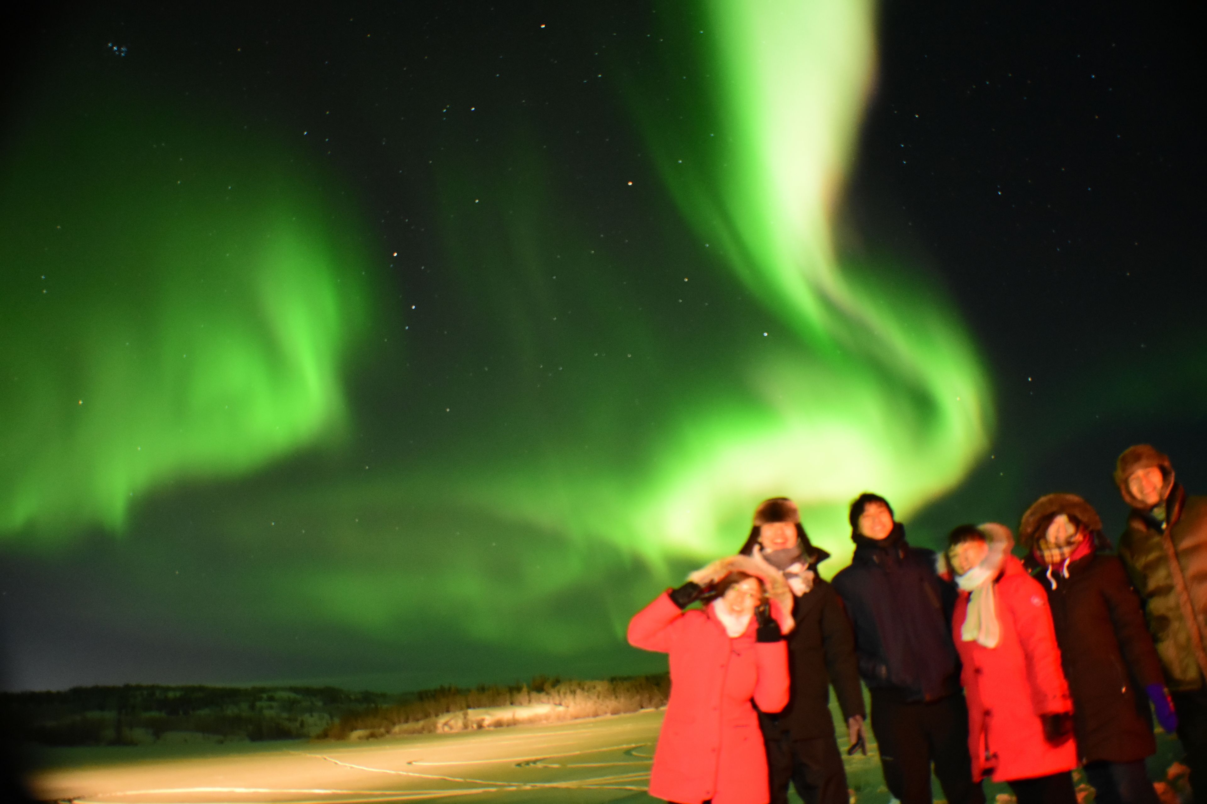 Un gruppo di persone in un paesaggio innevato con vista sull'aurora boreale.