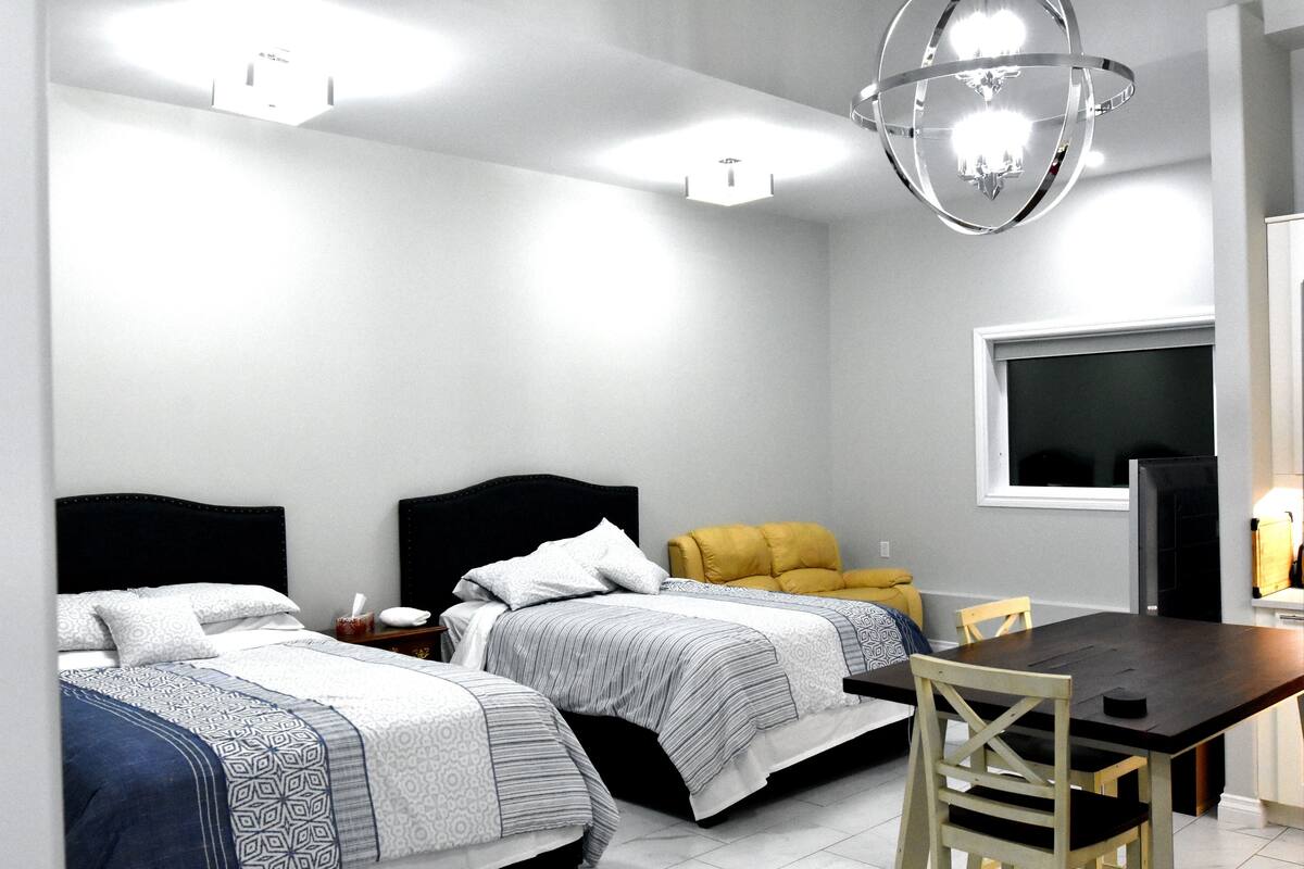 A hotel room with two beds, a dining table, and a TV.