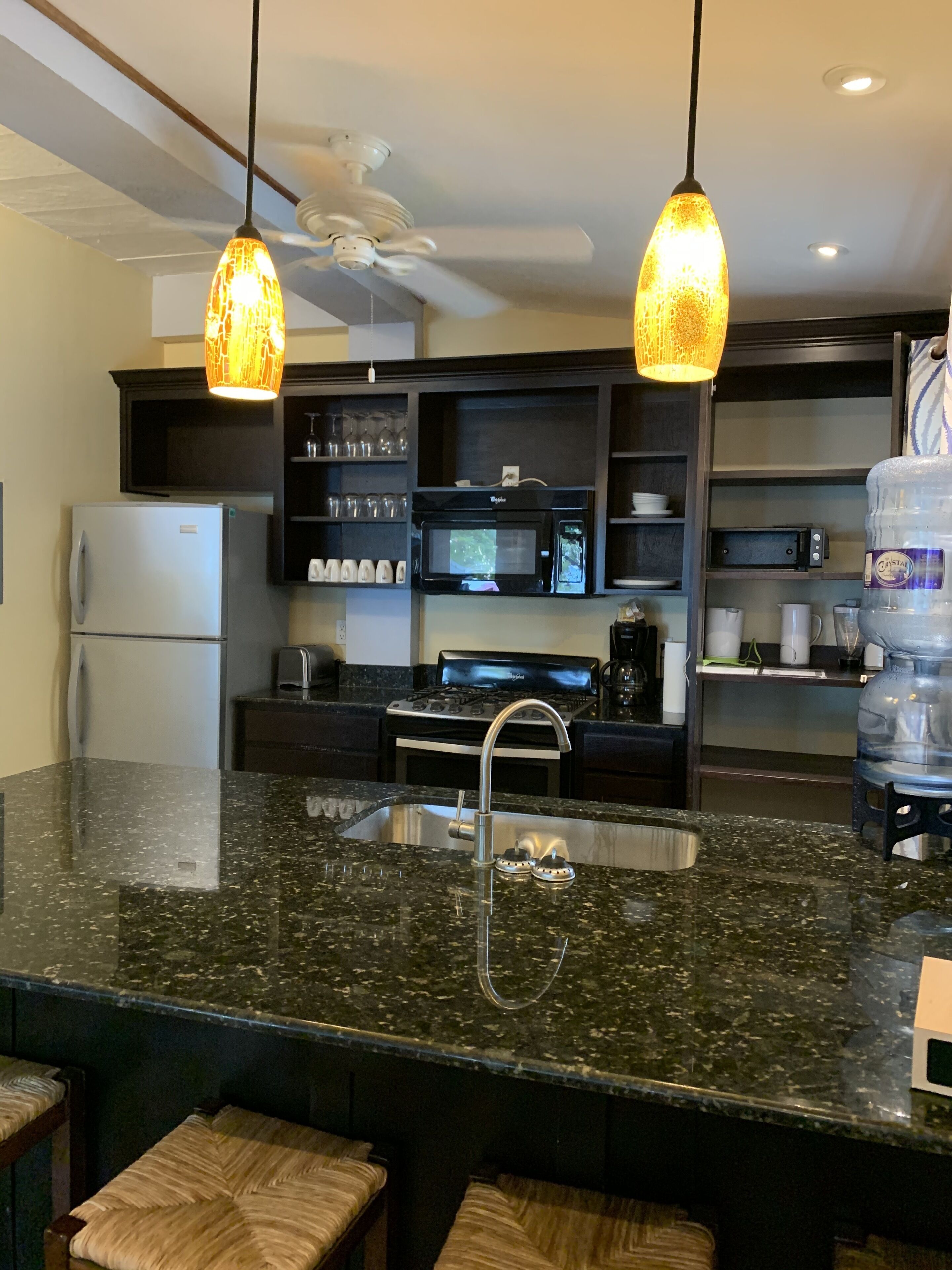 Una cocina moderna con encimeras de granito, electrodomésticos de acero inoxidable e iluminación colgante.
