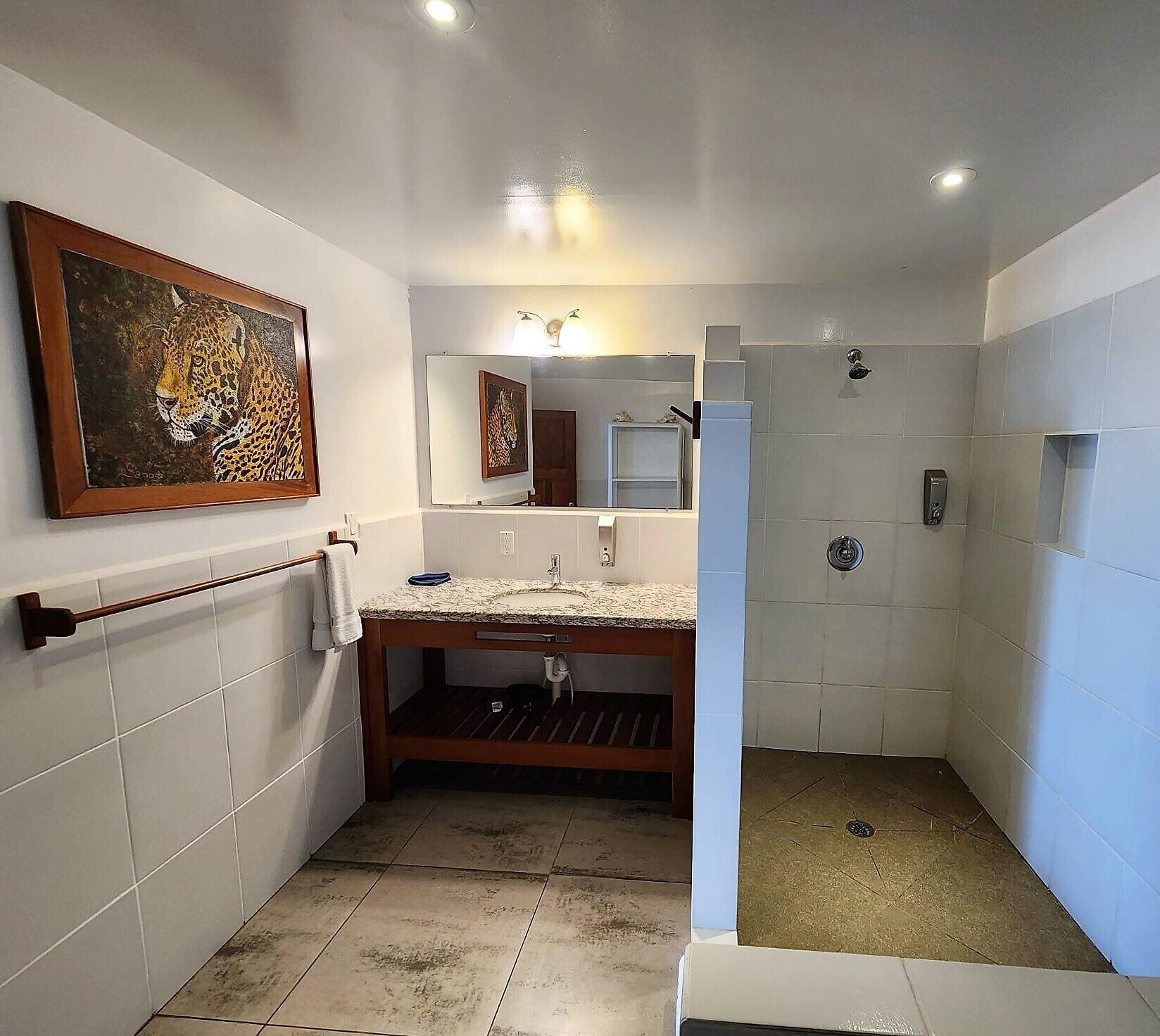 A bathroom with a marble sink, a wooden towel rack, a mirror, and a shower area.