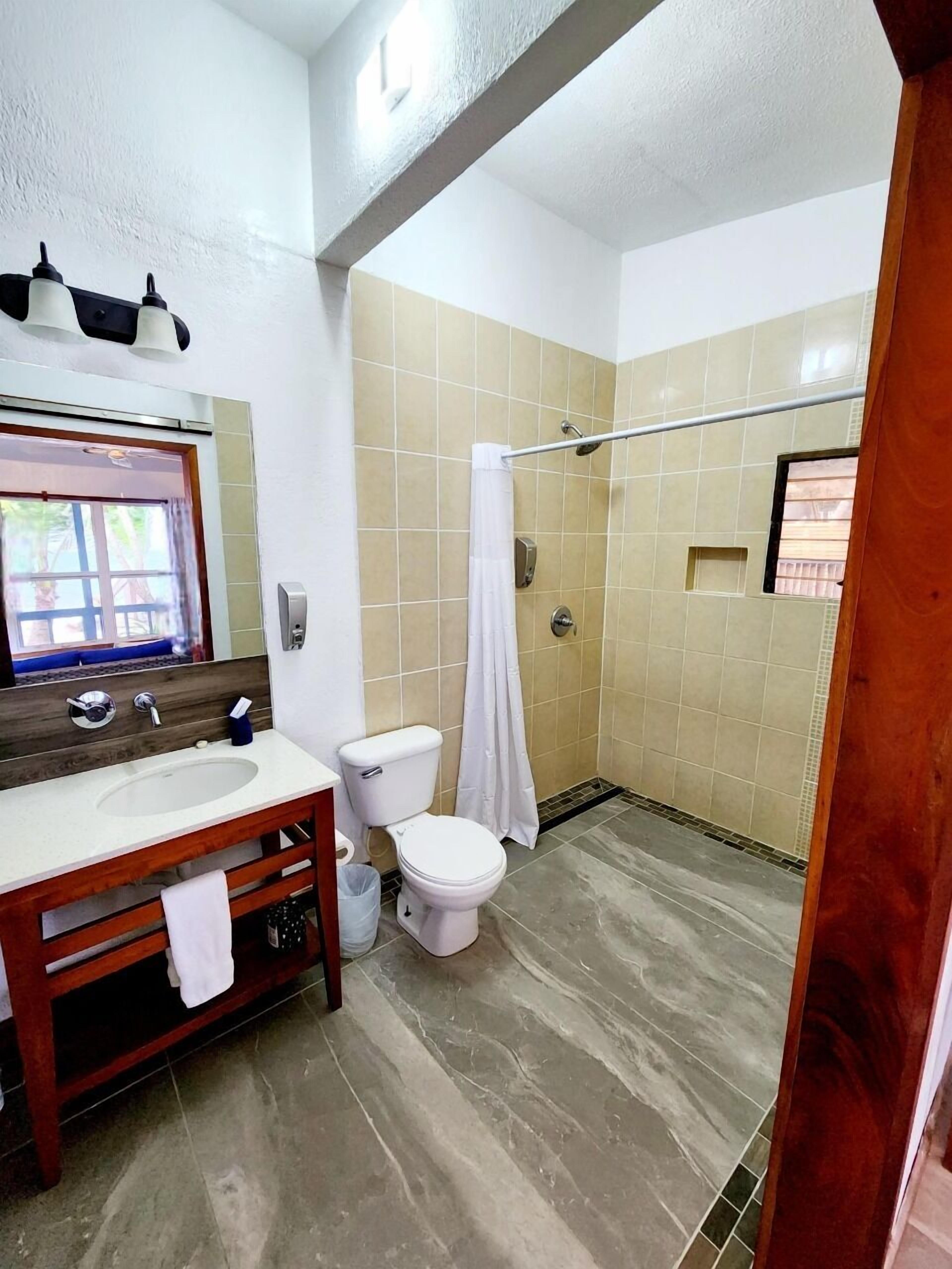 A bathroom with a wooden vanity, a toilet, a shower with a glass door, and a mirror above the vanity.
