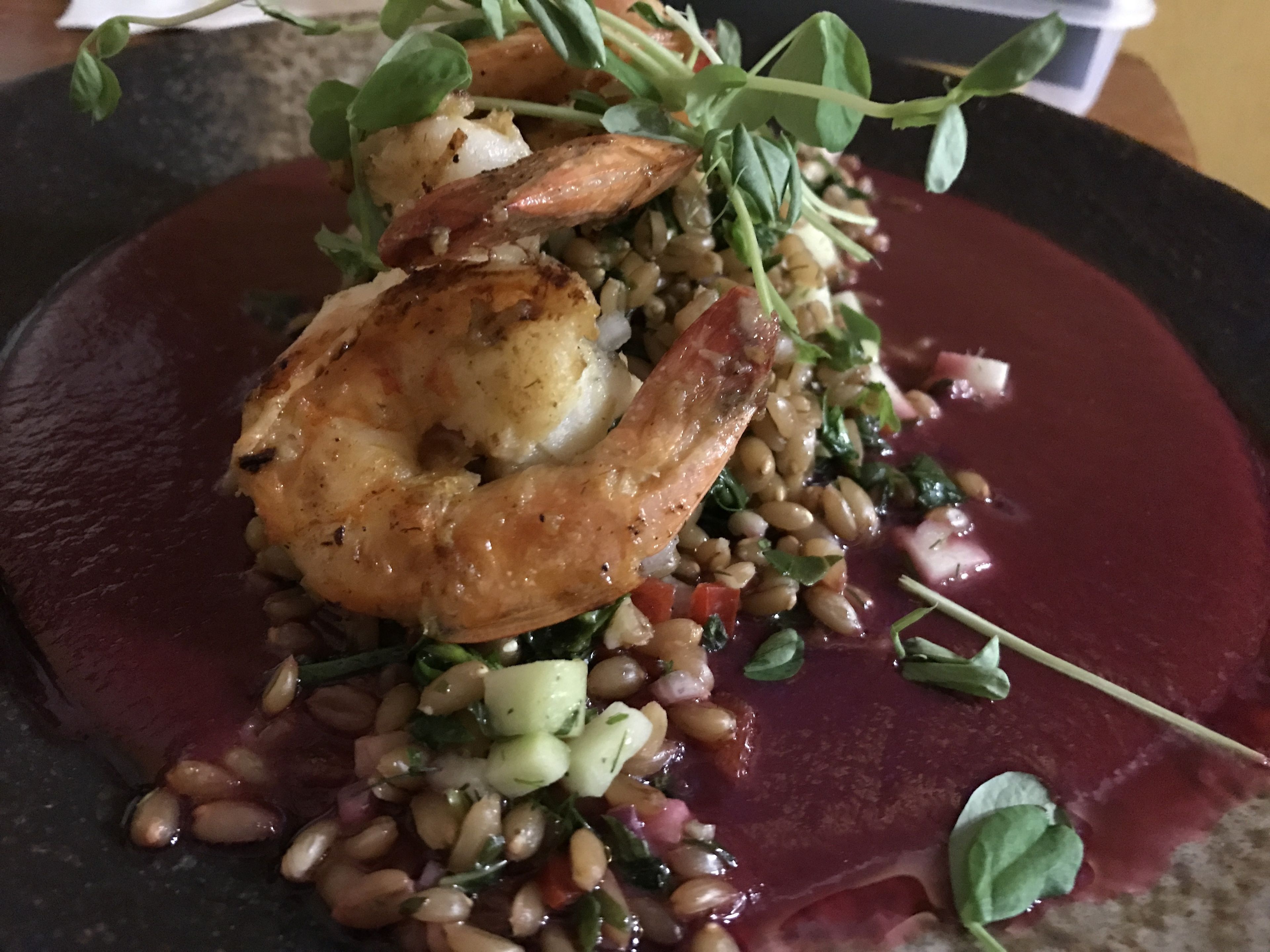 Een bord eten met garnalen, bonen en groene bladgroenten.