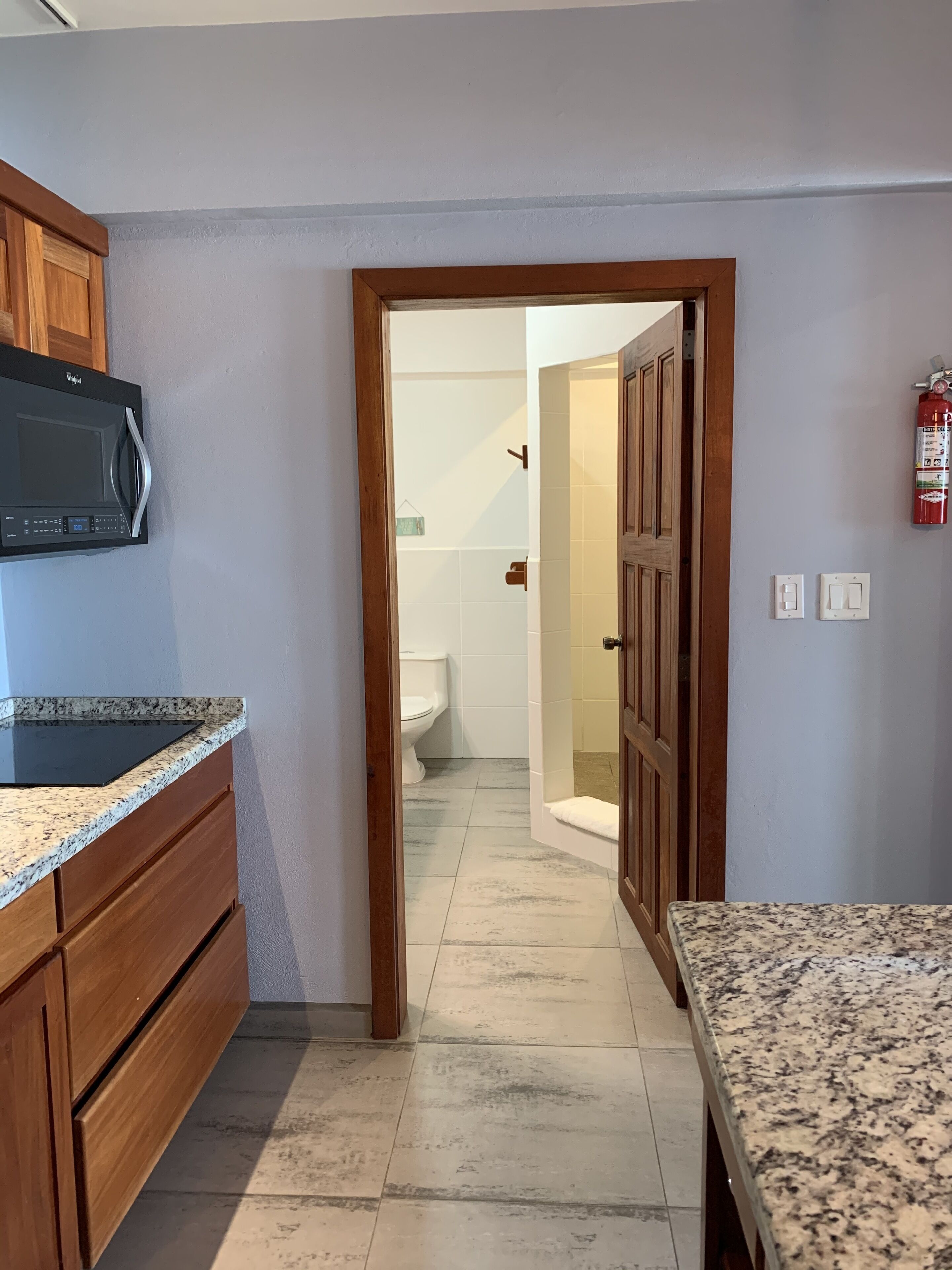 A kitchen with granite countertops, wooden cabinets, and a black microwave.