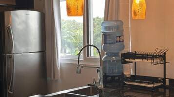 Una cocina moderna con un refrigerador de acero inoxidable, un lavamanos con un grifo original y luces colgantes.