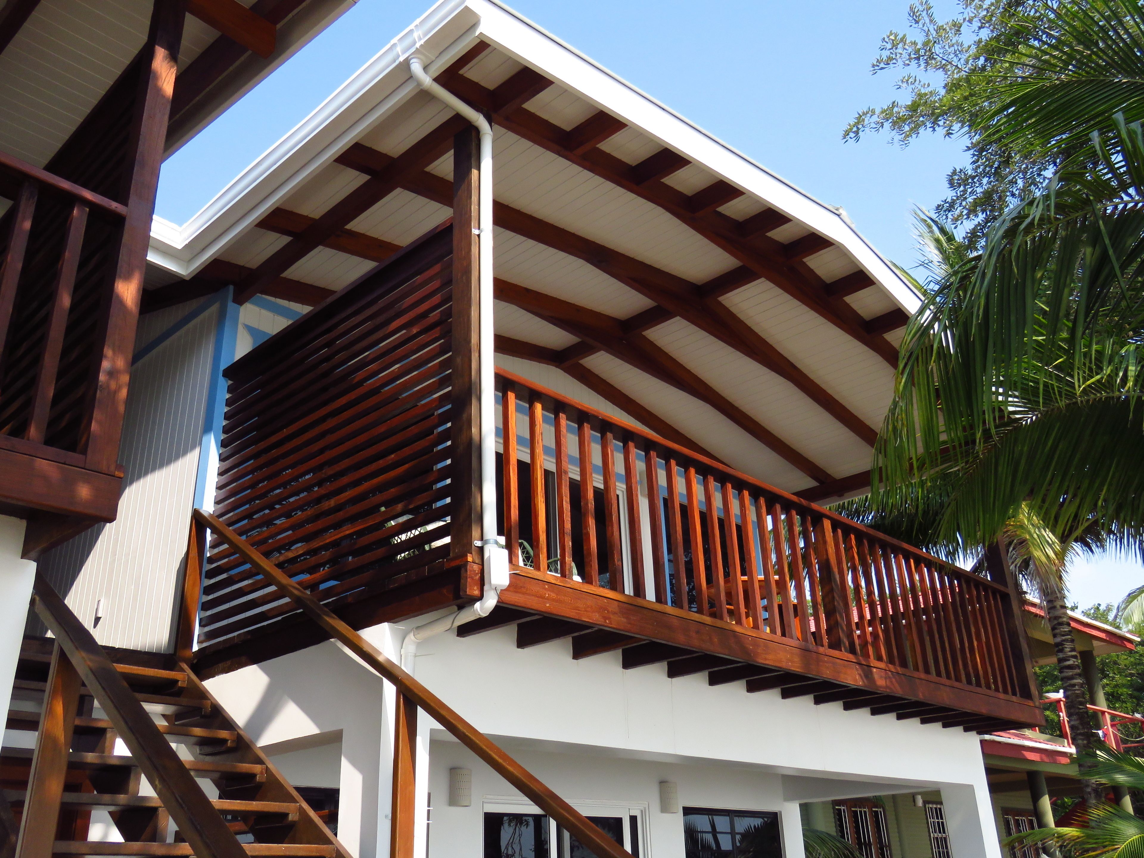 Un edificio de dos pisos con balcón, barandilla de madera y escalera.