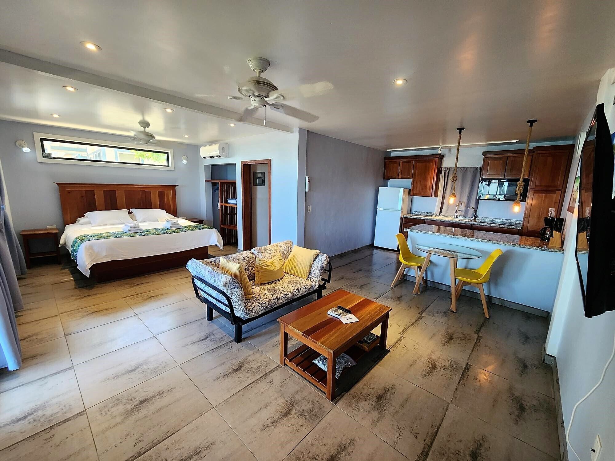Una habitación de hotel moderna con cama, sofá, mesa de centro y una kitchenette.