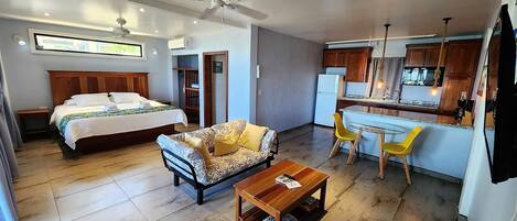 Una habitación de hotel moderna con cama, sofá, mesa de centro y una kitchenette.
