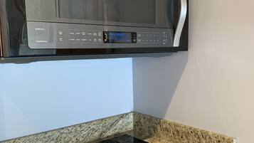 A Whirlpool microwave oven mounted above a granite countertop with a built-in induction cooktop.
