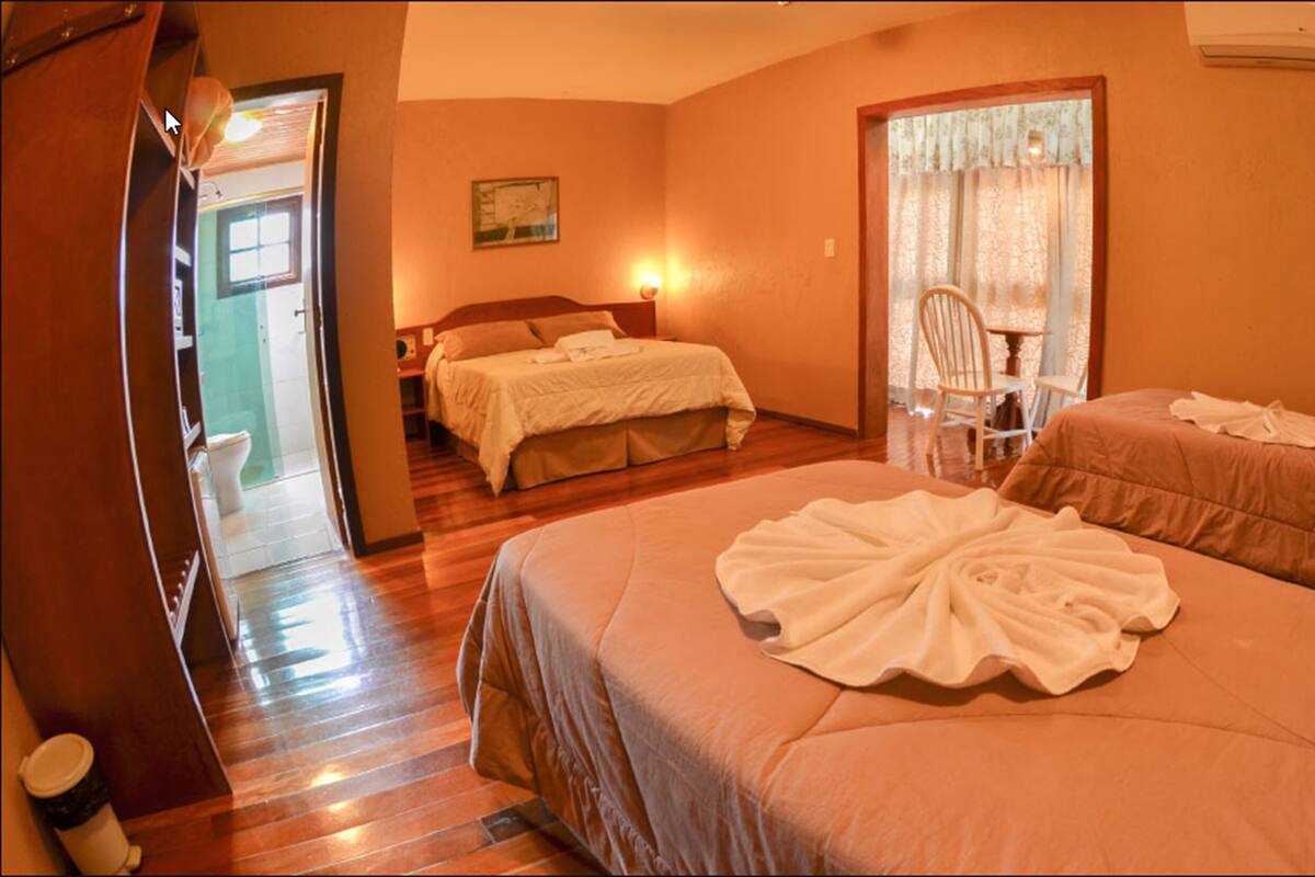 A hotel room with two beds, a chair, a television, and a window with curtains.