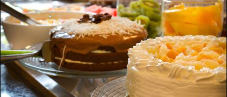 Una mesa de postres con varios pasteles y frutas.