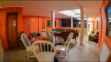 A room with a pool table, chairs, a sofa, and a window.