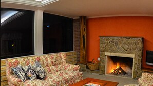 A living room with a fireplace, floral-patterned sofa, and a coffee table. - Hotel Aconchego da Serra (Gramado)