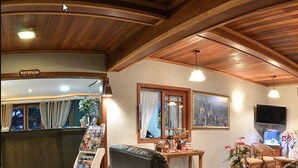 A spacious living area with a wooden ceiling, a reception desk, a television, and comfortable seating. - Hotel Aconchego da Serra (Gramado)