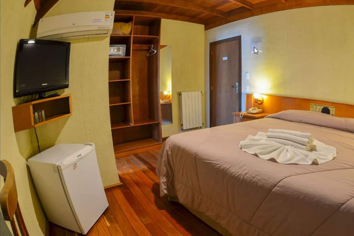 A hotel room with a bed, a television, a refrigerator, a wardrobe, and a bathroom.