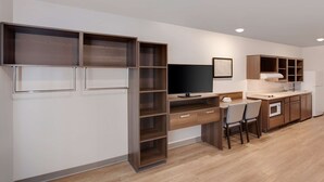 Een moderne keuken met inbouwmeubels, een eethoek met stoelen, en een flatscreen televisie aan de wand bevestigd.