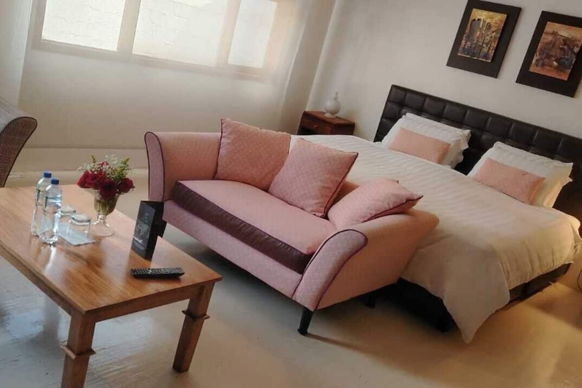 A bedroom with a bed, a sofa, a coffee table, and a nightstand.