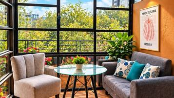 Un interior modern amb una taula de vidre, dos sofàs i vista a la verdura exterior.