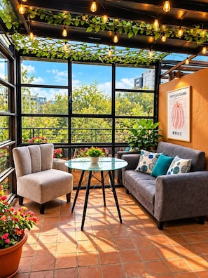A modern interior with a glass table, two sofas, and a view of greenery outside. - Dolce Lobo Boutique Stay (Quito)