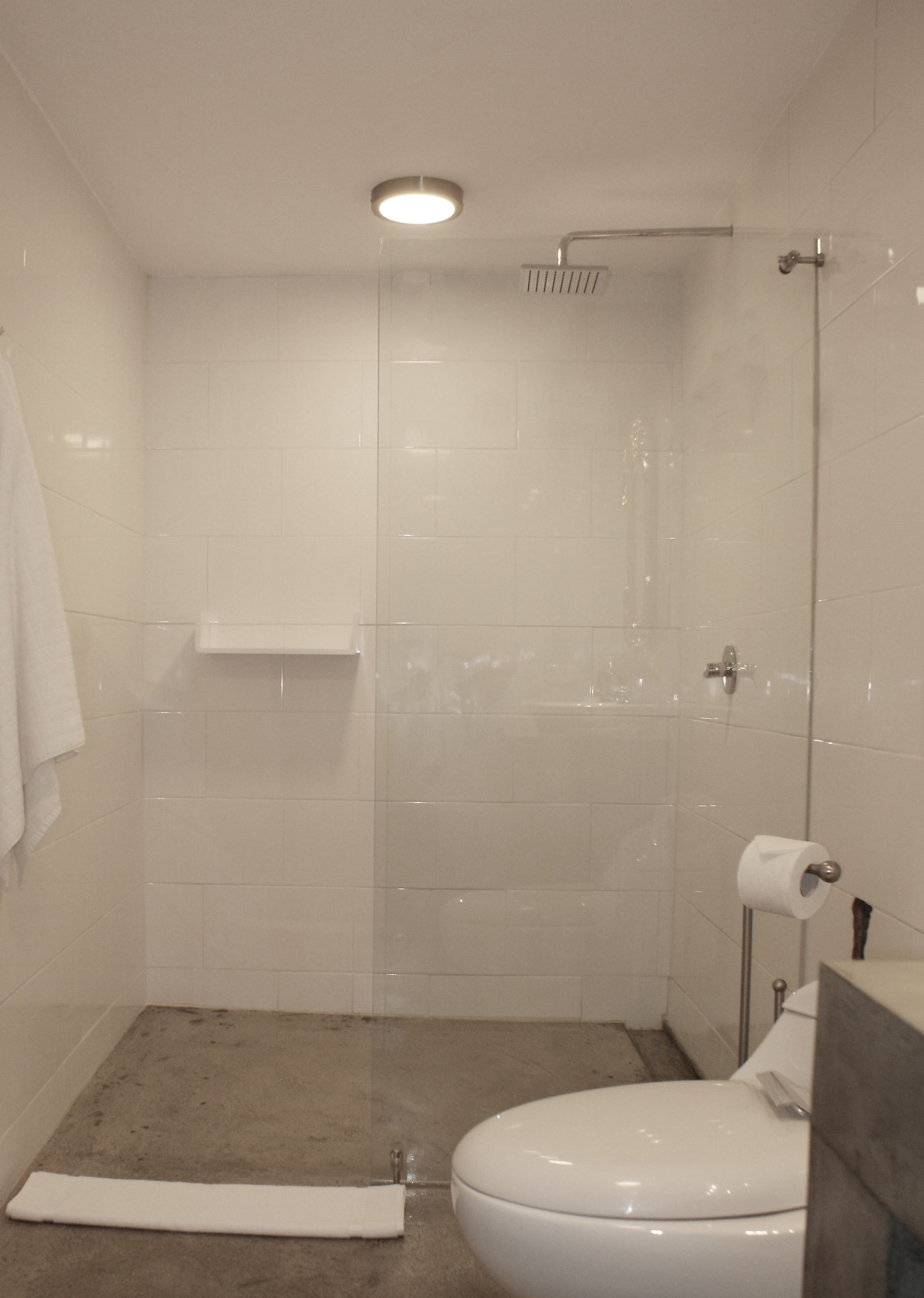 A bathroom with a shower, toilet, and a towel rack.