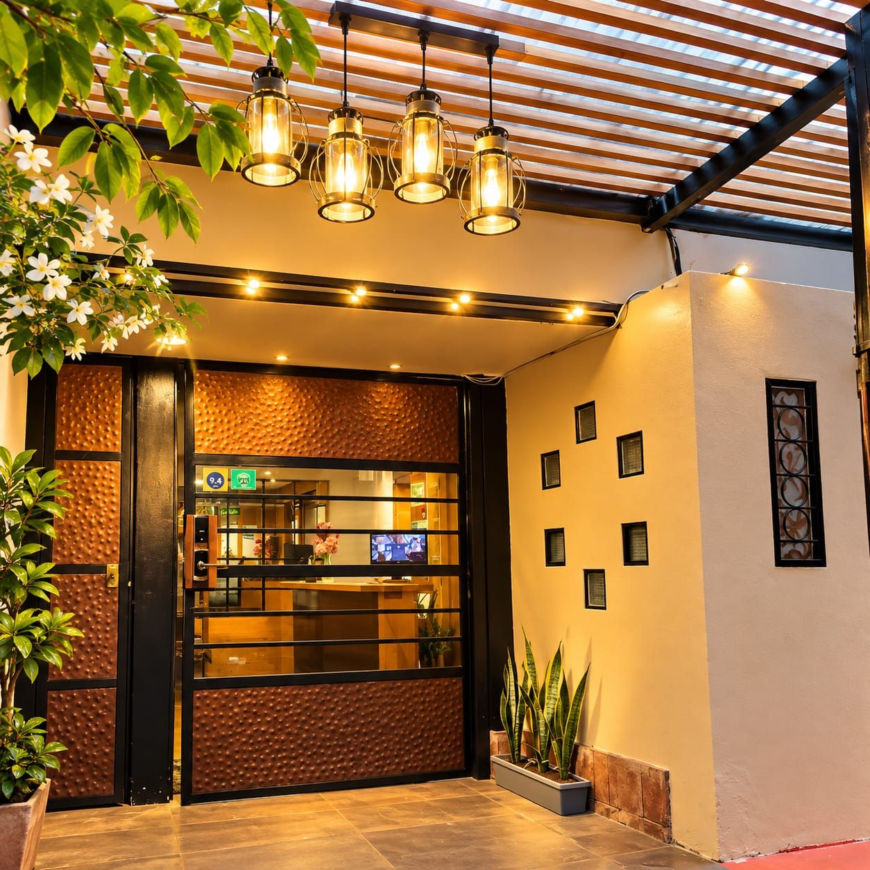Entrada d'hotel amb una recepció, un sostre de fusta i una planta a l'esquerra.
