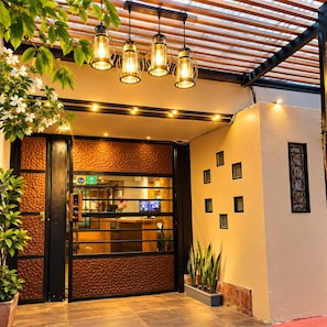 A hotel entrance with a reception desk, a wooden ceiling, and a plant on the left. - Dolce Lobo Boutique Stay (Quito)