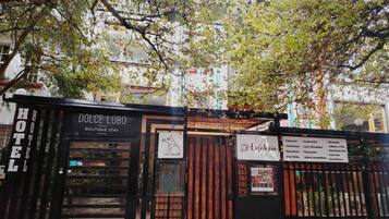 A hotel entrance with a sign for 'Dolce Lobo Boutique Stay' and a cafe menu board.